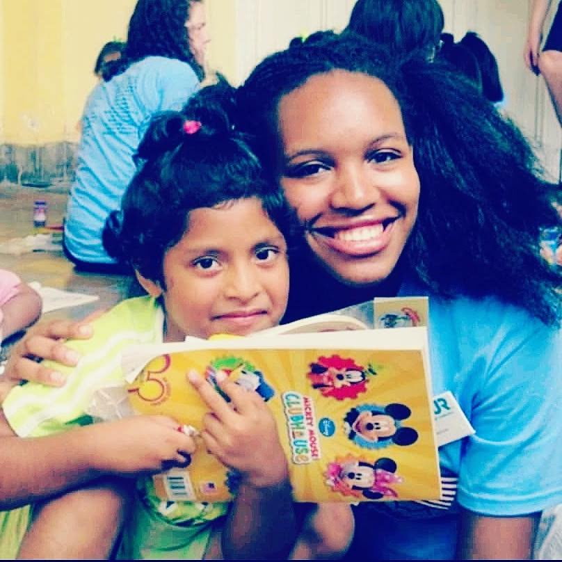 Renada smiling while reading with a child